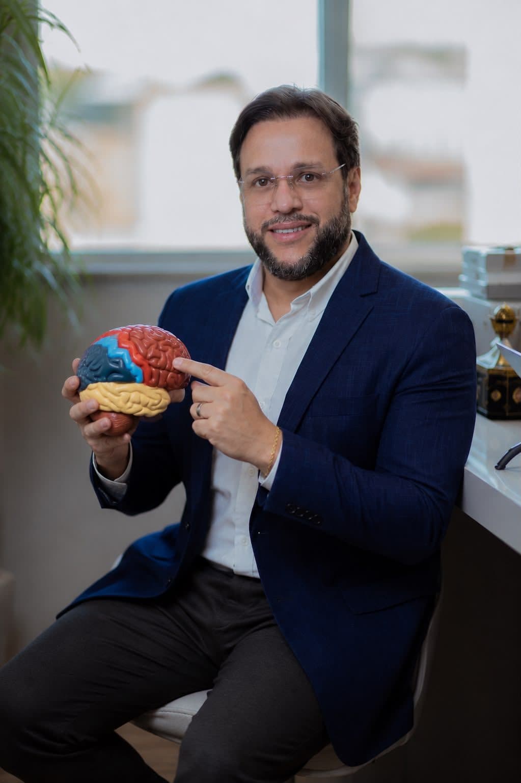 Dr. Renato Pacheco apontando para um modelo anatômico de cérebro